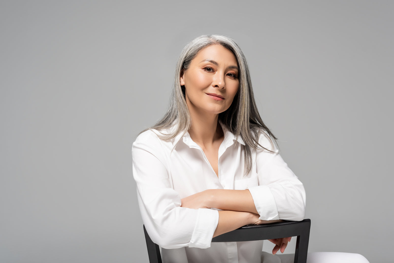 Confident looking asian woman with gray hair on chair | Parisians Pure Indulgence | How to age with beauty and confidence