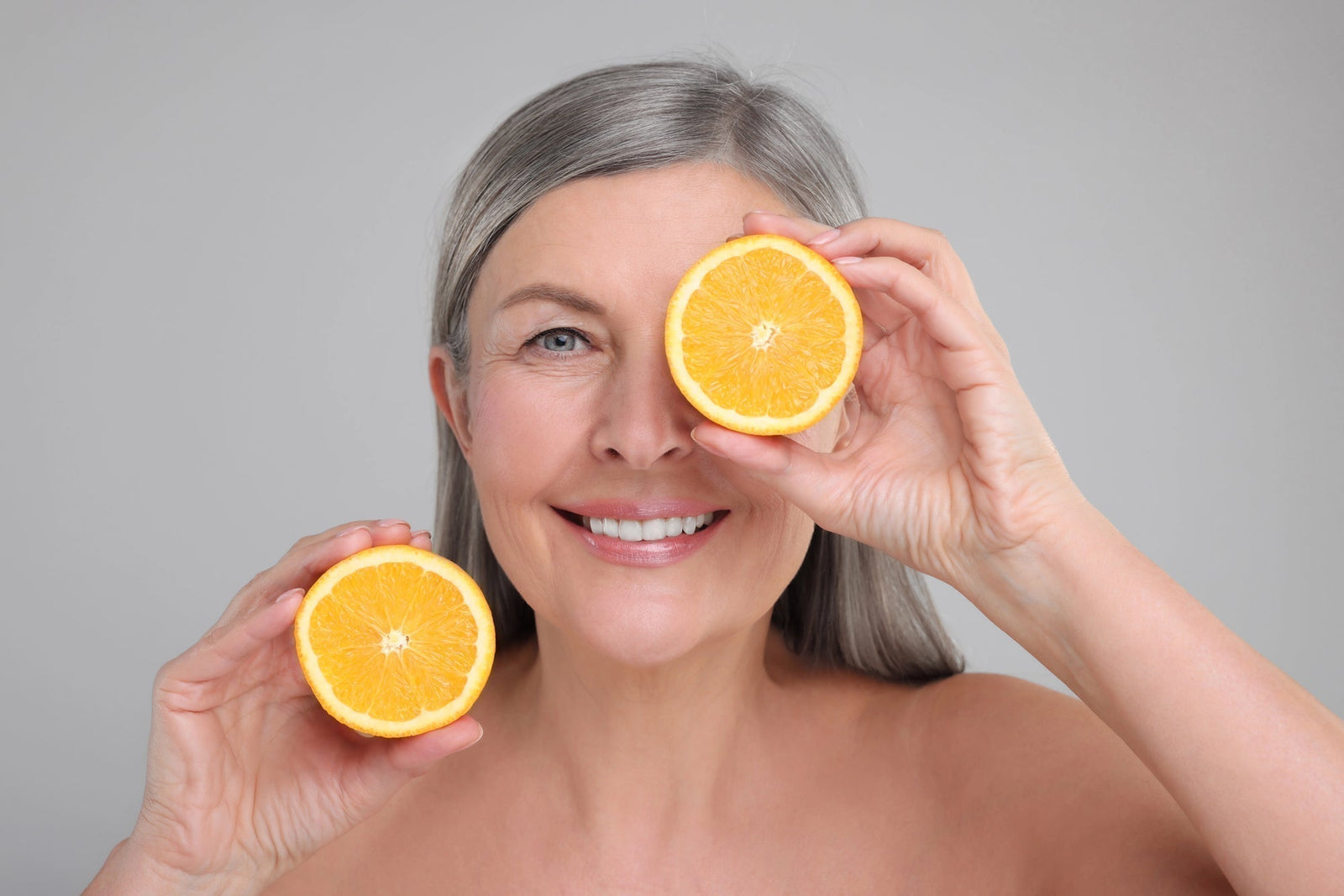 Mature woman holding orange halves | Best Vitamin C Facial Serum: Parisian's Pure Indulgence Skin care