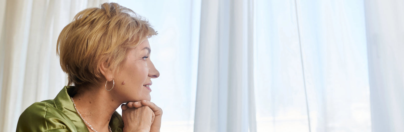 Woman looking out a window at green space | Parisians Pure Skincare