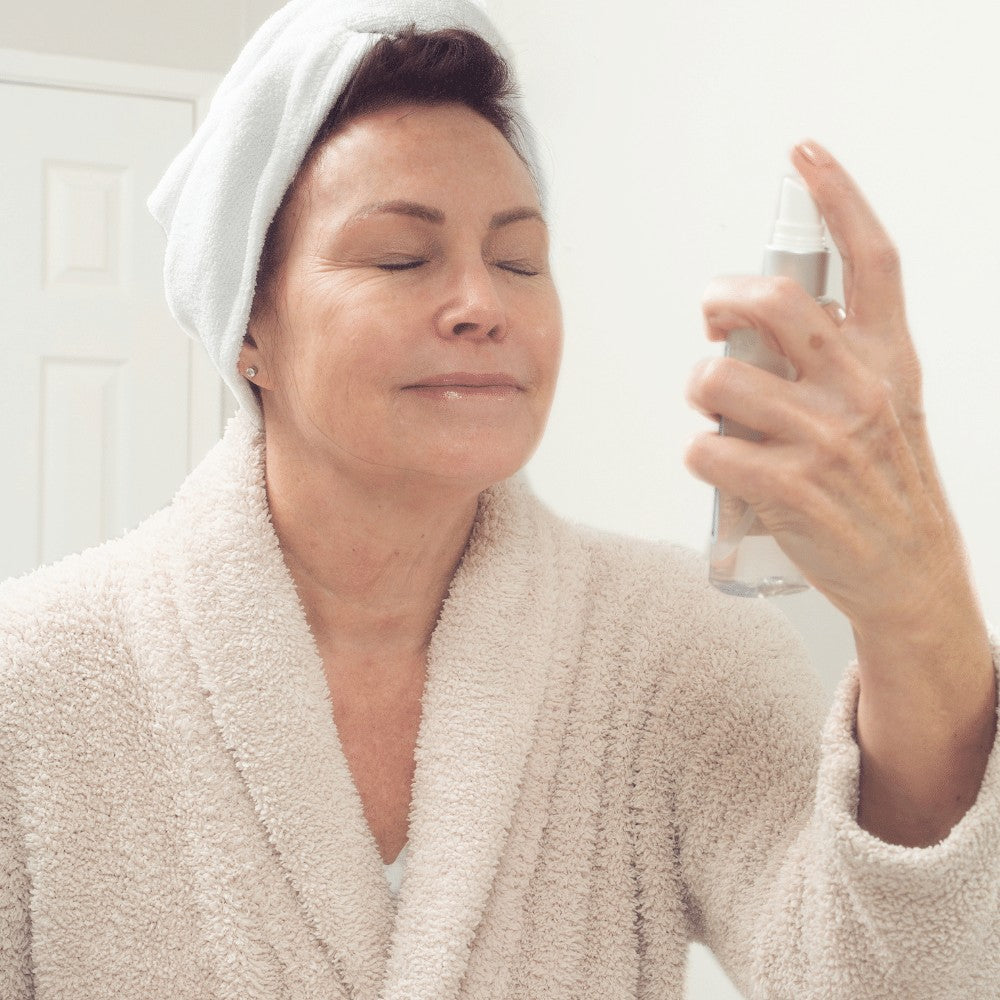 Woman applying toner mist to face