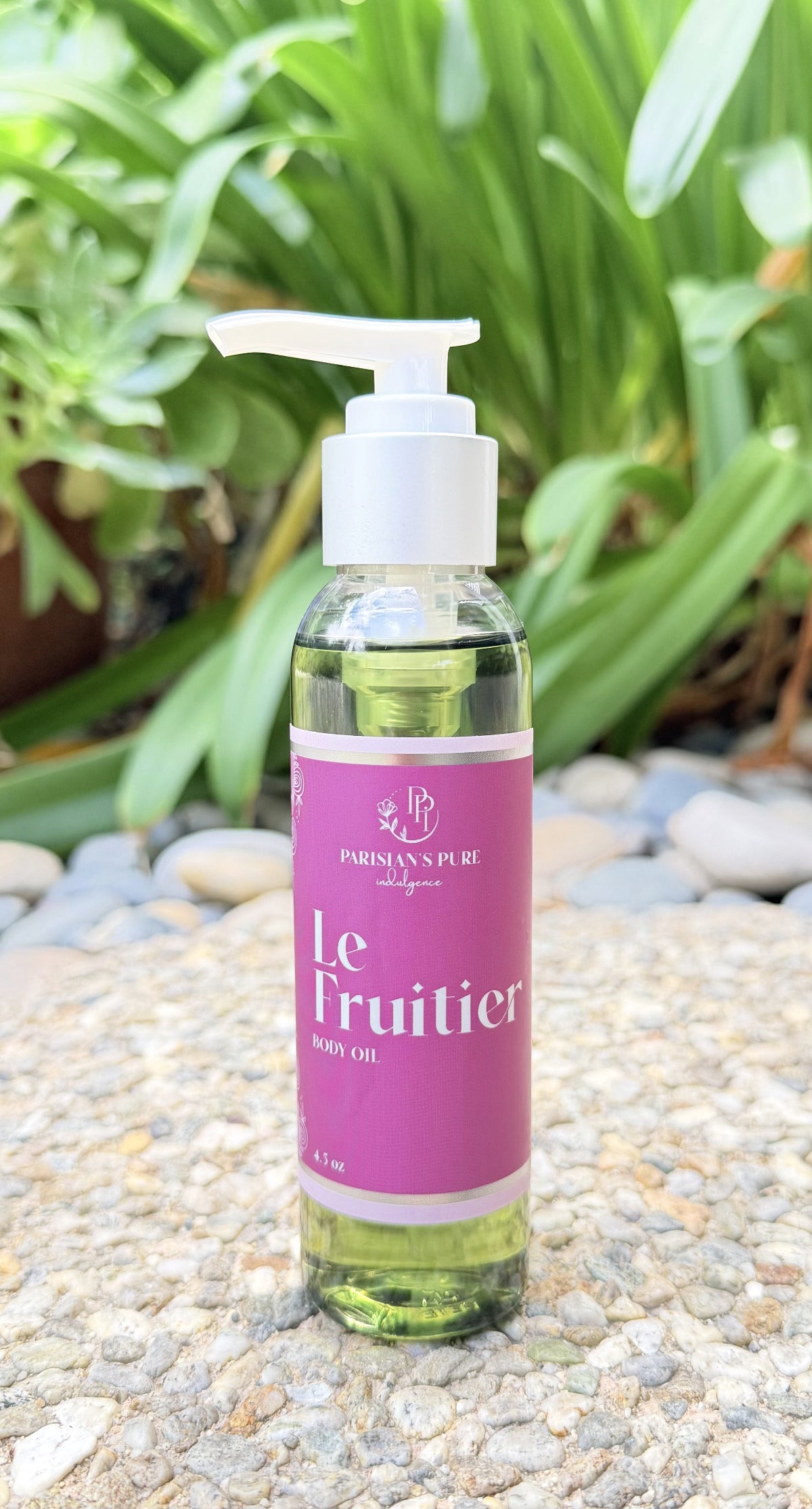Bottle of 'Le Fruitiér' product on a pebbly surface with greenery in the background
