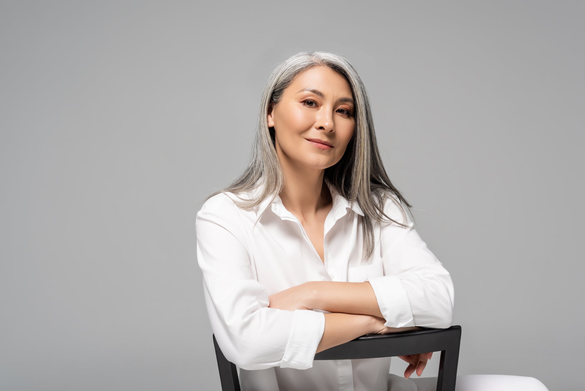 Confident looking asian woman with gray hair on chair |  Parisians Pure Indulgence | How to age with beauty and confidence