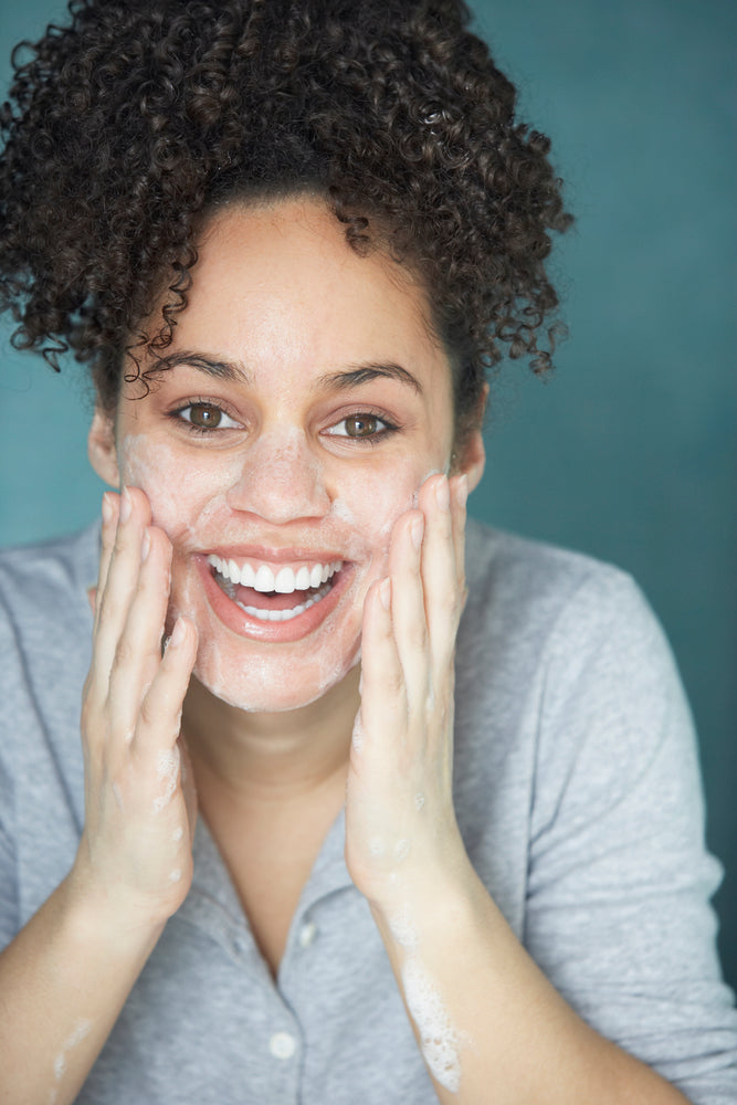beautiful woman exfoliating her skin - 4 ways exfoliation can help you look younger