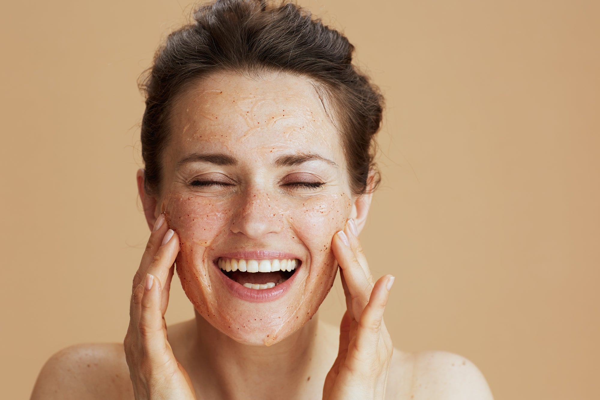 beautiful woman exfoliating her skin - 4 ways exfoliation can help you look younger