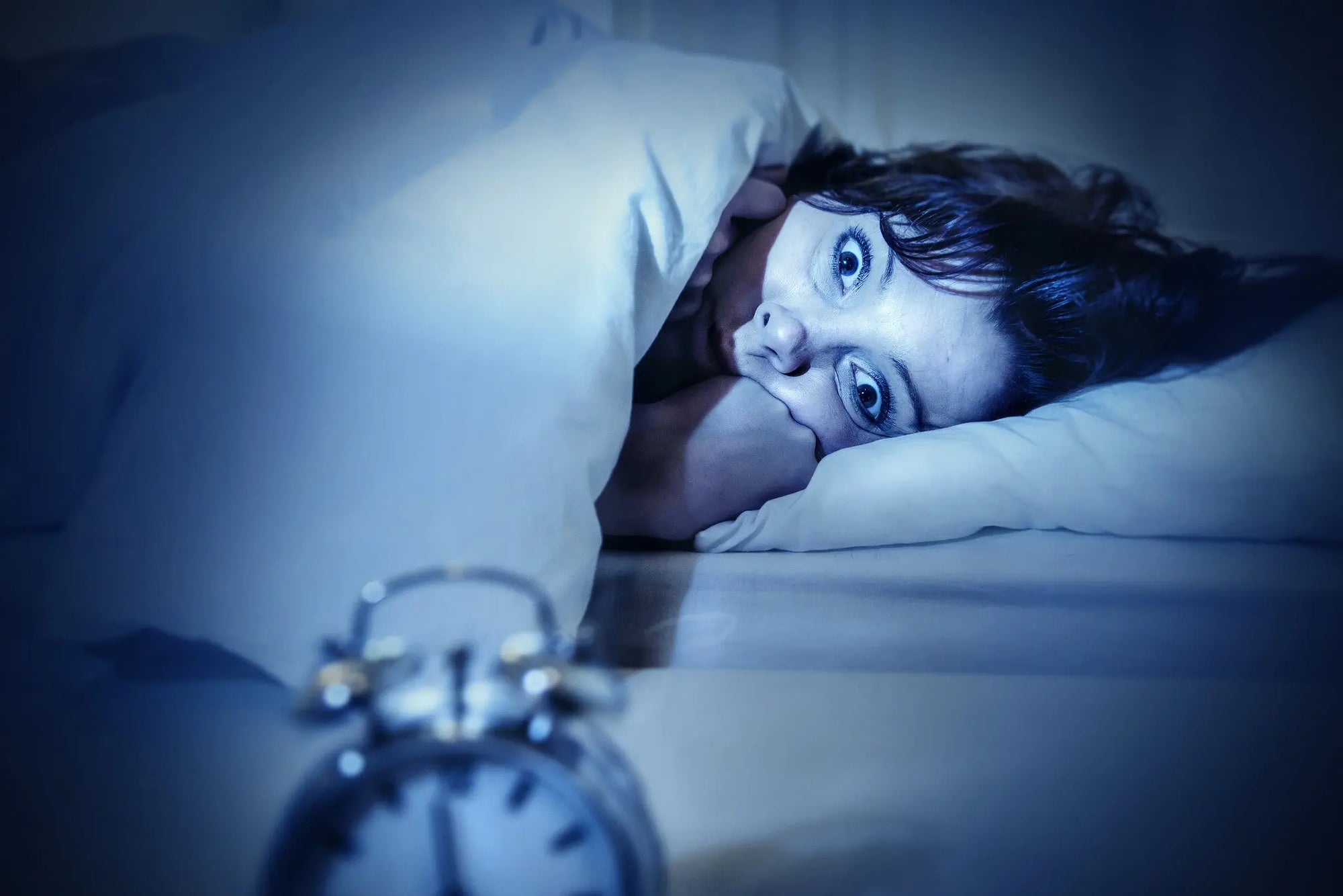 Woman in bed looking fearful |The Top 5 Fears Women Have After 50 | Parisians Pure Indulgence
